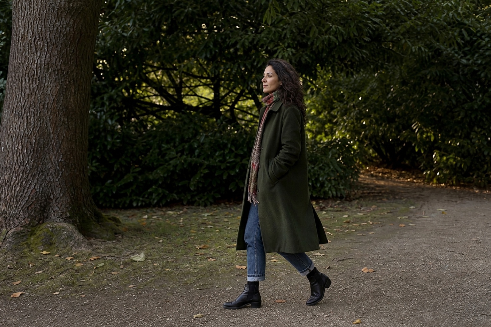 A woman walking beside mature trees